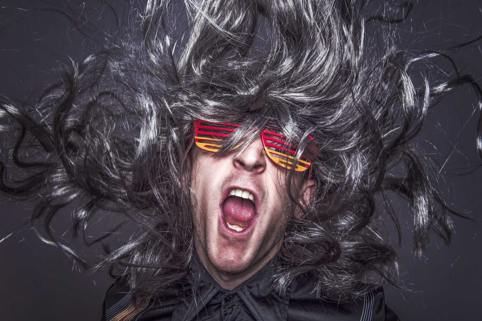 person wearing a big grey wig and colorful glasses enjoying music
